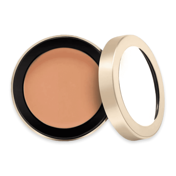 Jane Iredale Enlighten Concealer in geöffneter runder Dose mit beigem Deckel auf grünem Hintergrund.