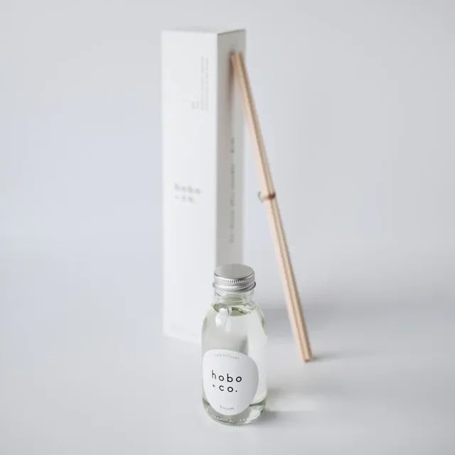 Hobo & Co. Raumduft mit Flasche und Holzstäbchen vor weißem Hintergrund.